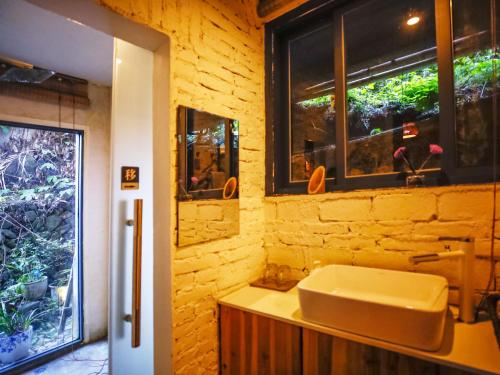 Tulou Herongzhuang Inn في Nanjing: حمام مع حوض ونوافذ