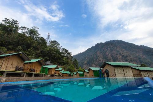 a group of huts next to a swimming pool at Camp Bagheera in Rishīkesh