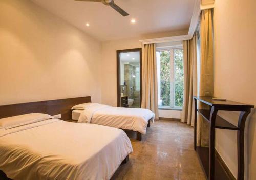 a hotel room with two beds and a window at Villa Esencia by VEO - Part of StayVista in Siolim