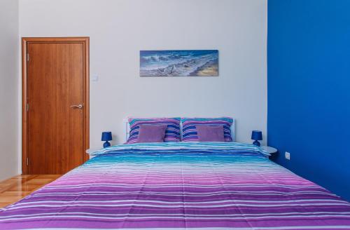 a blue bedroom with a purple bed with purple pillows at Villa Sladovic in Herceg-Novi