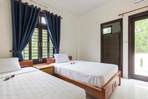a bedroom with two beds and a window at New Destination Hoi An in Hoi An