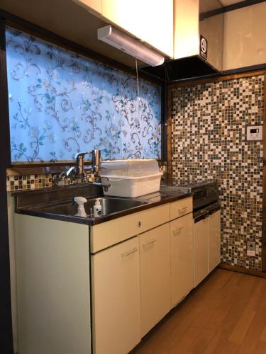 a kitchen with a sink and a tile wall at Rengeso in Tokyo