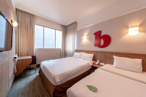 a hotel room with two beds and a red sign on the wall at Hotel Bencoolen Singapore in Singapore