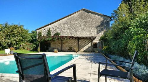 une maison avec une piscine et deux chaises dans l'établissement Cottages de Garrigue, à Fonroque