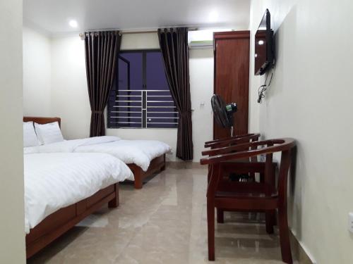 a bedroom with two beds and a television on a wall at Guesthouse Anh Khang in Ha Long