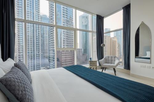 a bedroom with a large bed and large windows at Fantastay - Clara Dubai Marina in Dubai