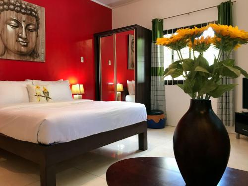 1 dormitorio con 1 cama y un jarrón con flores en Nora's Place en Panglao City