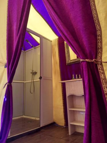 a bathroom with purple curtains and a shower at Sahara Majestic Luxury Camp in Merzouga