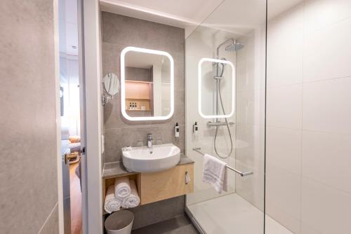 a bathroom with a sink and a shower with a mirror at WestCord Hotel Delft in Delft