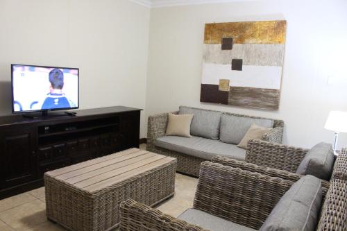 a living room with wicker furniture and a flat screen tv at Vista Bonita Apartments in Mossel Bay