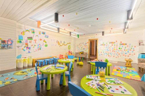 a preschool room with tables and chairs and a play area at Style Hotel Grifone in Madonna di Campiglio