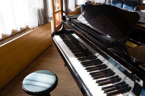 a piano with a chair next to a window at Style Hotel Grifone in Madonna di Campiglio