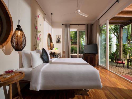 a bedroom with a large white bed and a patio at AIRA Boutique Hoi An Hotel & Villa in Hoi An