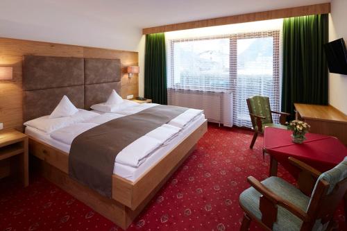 ロイテにあるPension Hohenrainerの大きなベッドとデスクが備わるホテルルームです。