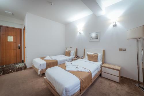 two beds in a room with white walls at Bushi Resort & SPA in Skopje