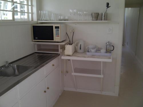 a small kitchen with a sink and a microwave at Loader Street Cottage in Cape Town
