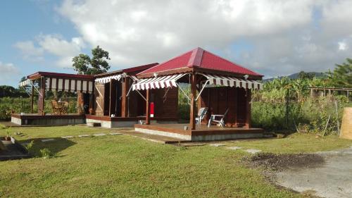 a gazebo with a red roof in a yard at le "BWA ' KAO" in Capesterre-Belle-Eau