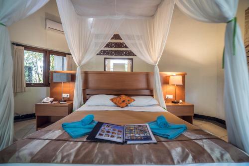 a bedroom with a bed with blue slippers on it at Gajah Biru Bungalows in Ubud