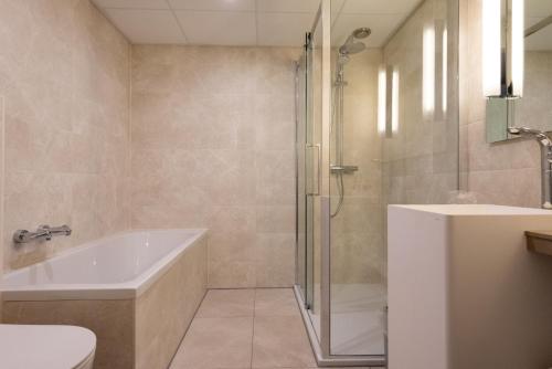 a bathroom with a shower and a tub and a toilet at WestCord Strandhotel Seeduyn in Oost-Vlieland