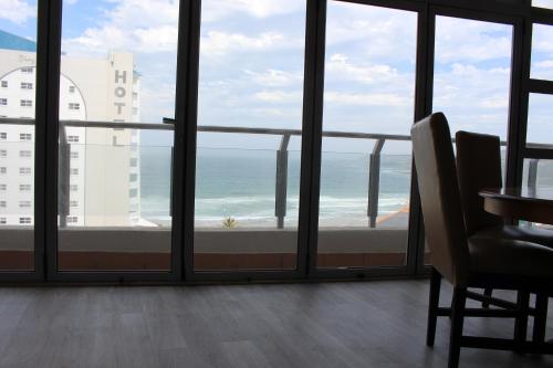 a room with a view of the ocean from a balcony at Vista Bonita Apartments in Mossel Bay