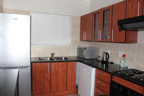 a kitchen with wooden cabinets and a stainless steel refrigerator at Vista Bonita Apartments in Mossel Bay