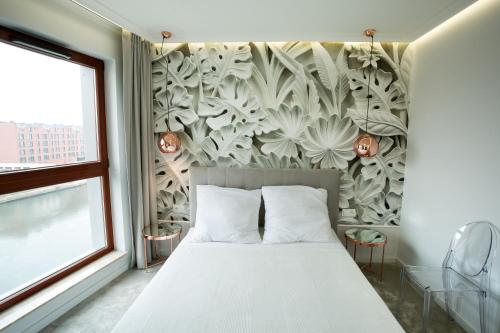 sypialnia z białym łóżkiem i malowidłem ściennym w obiekcie Apartament z basenem i widokiem na Motławę w Gdańsku