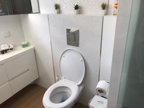 a bathroom with a toilet with a toilet paper dispenser at Charming Unit with Pool and Great Amenities in Rishon LeẔiyyon