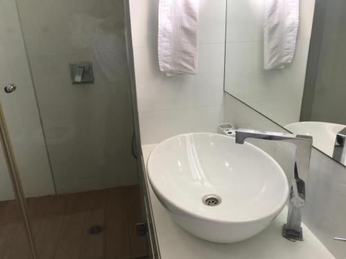 a white bathroom with a sink and a shower at Charming Unit with Pool and Great Amenities in Rishon LeẔiyyon