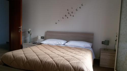 una camera da letto con un letto con cuscini bianchi e uccelli sul muro di Rinaldi House a Torriana
