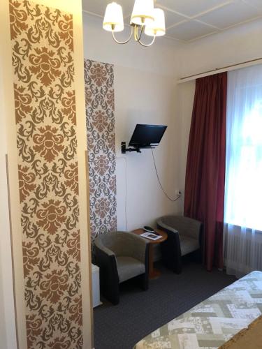 ベルリンにあるホテル カステル アム クアフュルステンダムのベッド1台、椅子、窓が備わる客室です。