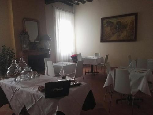 a room with white tables and chairs and a window at Locanda Al Portone in Scandiano