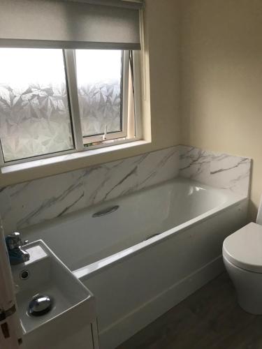 a bathroom with a tub and a toilet and a window at 8 Queenora Avenue in Portstewart