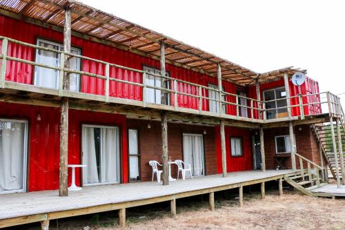 a red building with two white chairs on the porch at LA PALOMA CONTAINERS SUITES in La Paloma