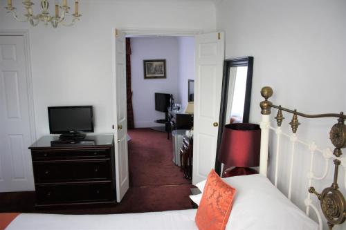 a bedroom with a bed and a television and a hallway at Thanington Hotel in Canterbury