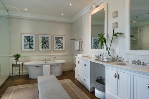 a bathroom with a tub and two sinks and a bath tub at The Residence @ Vrede & Lust in Franschhoek