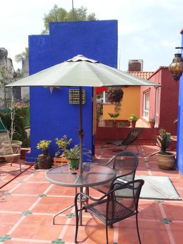 a table and chairs under an umbrella on a patio at Maria Del Alma House in Mexico City