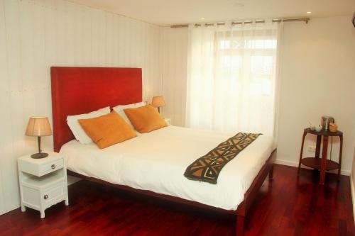 a bedroom with a bed with orange pillows and a window at Tavira House in Tavira