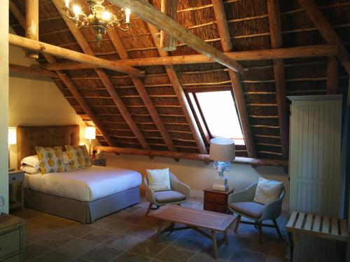 a bedroom with a bed and two chairs and a table at Gemoedsrus Farm in Stellenbosch