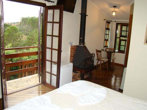 a bedroom with a fireplace and an open door with a view at Alpenhaus Pousada in Campos do Jordão