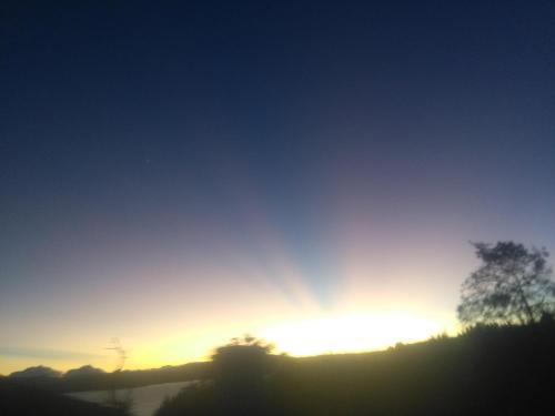a sunset over a hill with a tree in the foreground at La cabaña de sol in Aquitania
