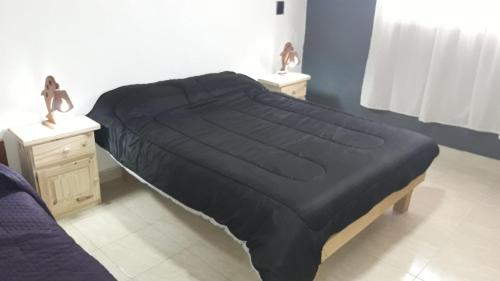 1 cama con edredón negro en un dormitorio en Lo de Marito en Balneario Claromecó