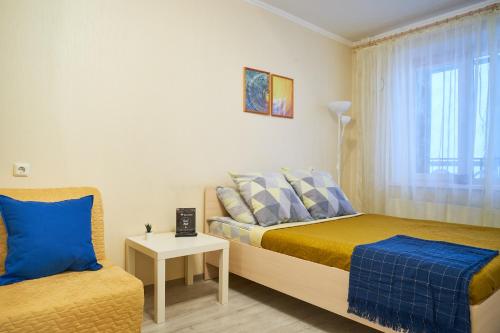 a bedroom with a bed and a chair and a window at "GOOD NIGHT" on Ovrazhniy 17 in Tomsk