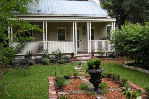 a white house with a porch and a yard with a garden sidx sidx at Flowertown Bed and Breakfast in Summerville