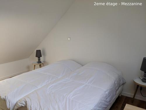 a white bed in a bedroom with two tables at Appartements Boulonnais in Boulogne-sur-Mer
