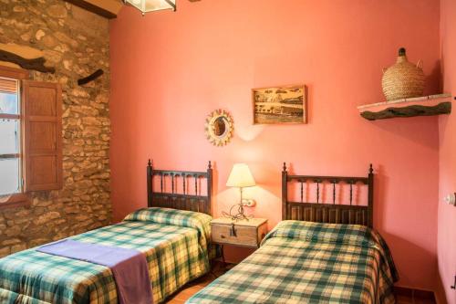 two beds in a room with pink walls and a window at Amborget in Sant Jordi