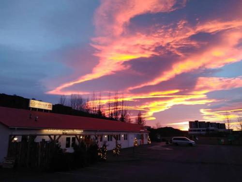 a sunset over a building in a parking lot at Tehúsið Hostel in Egilsstaðir