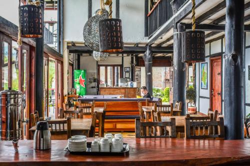 un restaurante con mesas y sillas de madera y una persona de fondo en Coffee Tree Boutique Hostel, en Salento