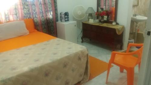 a bedroom with a bed and a chair and a dresser at Fay Guest House in Negril