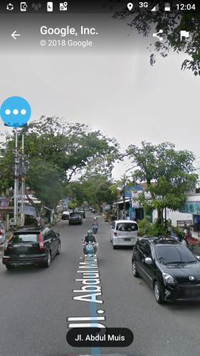 a street with cars parked on the side of the road at skyz hostel in Padang