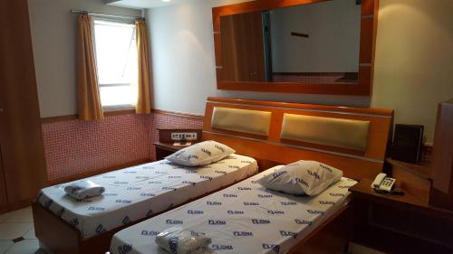 サンパウロにあるHotel Flor do Ipiranga (Adult Only)のベッド2台と鏡が備わるホテルルームです。